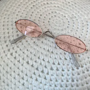 Nahaufnahme von retro Mini-Metallsonnenbrille mit ovalen Gläsern auf Strickgrund.