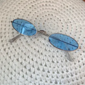 Nahaufnahme von Vintage Ovale Metall Sonnenbrille mit blauen Gläsern auf Strick Textur Hintergrund