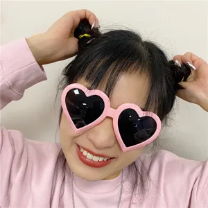 Pink heart-shaped novelty sunglasses detail view, fun party photo booth prop and funny item.