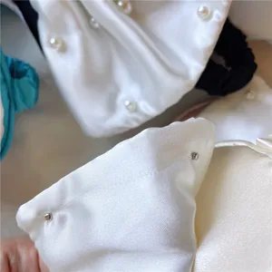 Detaillierte Nahaufnahme der Satin Perlen Schleife Schlaf-Schlafmaske mit feiner Stofftextur.