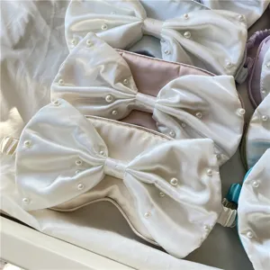 Detailaufnahme der Seidensatin Schlafmaske mit eleganter großer Schleife und Perlen für süße Träume.