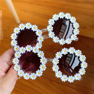 Close-up detail of trendy round sunglasses with white daisy floral frame decoration.