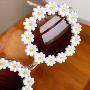 Close-up detail of trendy round sunglasses with cute white daisy flower decorations.