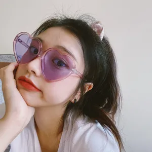 Nahaufnahme Detail der retro rosa herzförmigen Sonnenbrille am Model, trendiges Accessoire.