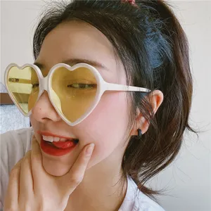 Retro rosa herzförmige Sonnenbrille Detailansicht mit grossem Rahmen und gelben Gläsern.