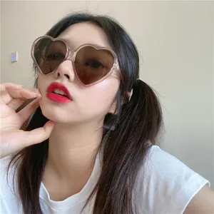 Nahaufnahme der süßen herzförmigen rosa Sonnenbrille am Modell, perfekter Retro-Modestil.