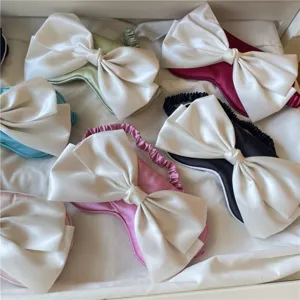 Vue détaillée de plusieurs masques de sommeil en satin avec de grands nœuds blancs.