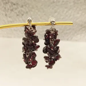 Vue détaillée de boucles d'oreilles pendantes en pierres de grenat rouge avec clous métalliques.