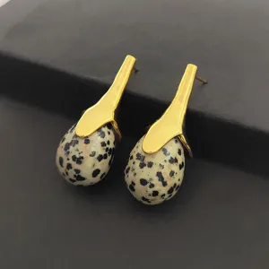 Gros plan détaillé des boucles d'oreilles pendantes en pierre naturelle style bohème.
