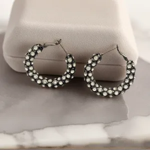 Gros plan de boucles d'oreilles créoles noires en cristal avec des strass étincelants pour femmes.