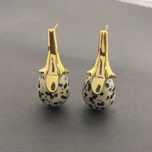 Gros plan détaillé des boucles d'oreilles pendantes en pierre naturelle style bohème chic.