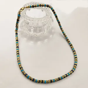 Collier ras de cou de perles colorees avec des disques metalliques et de pierres.