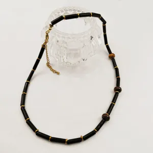 Collier de perles noires avec intermédiaires dorés et accents en pierre, bijou élégant et chic.
