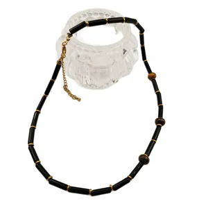 Collier de perles noires tendance avec des accents dorés et un design élégant pour femmes.