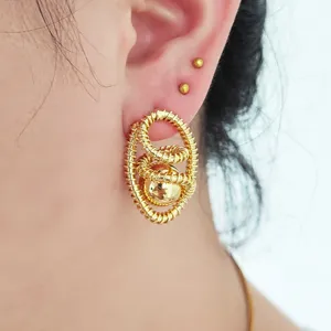 Gros plan détaillé de boucles d'oreilles ovales dorées enroulées avec une sphère brillante.