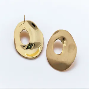 Gros plan détaillé de boucles d'oreilles dorées géométriques aux finitions polies et brossées.