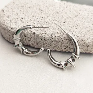 Gros plan de boucles d'oreilles créoles argentées au design unique de croissant de bambou.