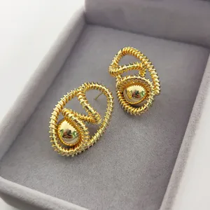 Gros plan détaillé de boucles d'oreilles spirales dorées vintage dans un écrin gris.