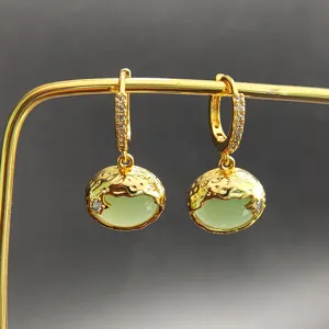 Gros plan détaillé de boucles d'oreilles pendantes dorées de style vintage avec des pierres vertes.