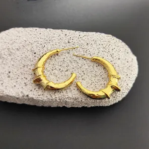 Vue détaillée de boucles d'oreilles créoles croissant de lune en bambou doré, chic.