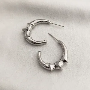 Vue détaillée de boucles d'oreilles croissant en métal argenté texture bambou.