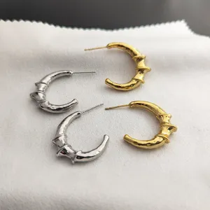 Gros plan sur des boucles d'oreilles tendance en métal croissant nœud de bambou aux détails originaux.