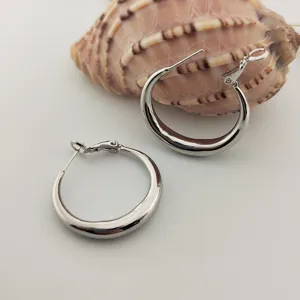 Gros plan de boucles d'oreilles créoles en métal argenté lisse, style élégant et polyvalent.
