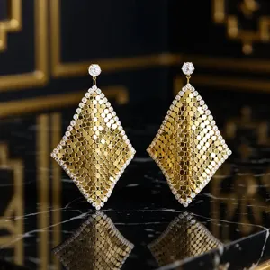 Gros plan détaillé de boucles d'oreilles pendantes géométriques ornées de strass étincelants.