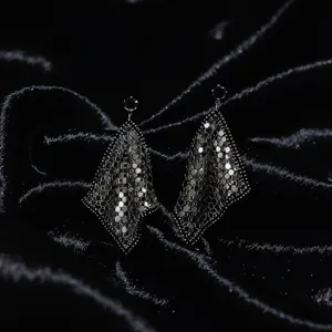 Gros plan détaillé de boucles d'oreilles pendantes à sequins sur fond de velours noir.