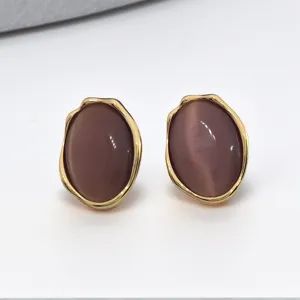Gros plan détaillé de boucles d'oreilles ovales irrégulières violettes à bordure dorée.