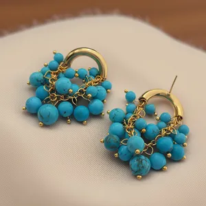 Gros plan de boucles d'oreilles vintage en turquoise, cerceau doré, détail de bijoux élégant.