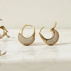 Gros plan detaille de magnifiques boucles doreilles creoles en zircone sur marbre clair.