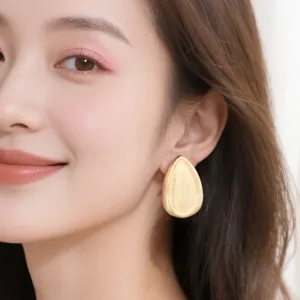 Gros plan détaillé sur les boucles d'oreilles minimalistes dorées brossées en goutte.