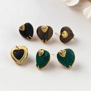Gros plan détaillé de boucles d'oreilles clous cœur en pierre naturelle avec finition dorée.