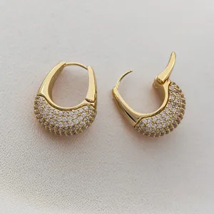 Gros plan de boucles d'oreilles créoles plaquées or avec un design pavé détaillé.