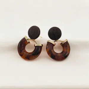 Gros plan de boucles d'oreilles vintage en bois et résine, montrant des détails élégants.