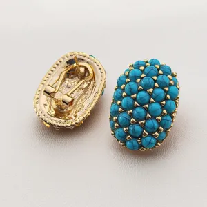 Boucles d'oreilles ovales turquoise vintage avec base en métal doré, détail de pierres précieuses.