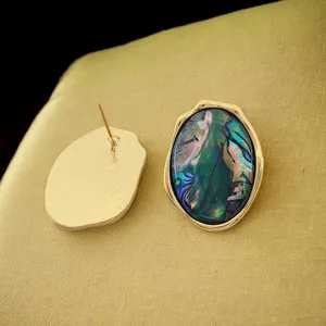 Gros plan de boucles d'oreilles ovales irrégulières en coquillage abalone naturel, or.