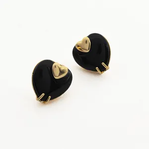 Gros plan de boucles d'oreilles cœur noir exquises avec accent doré, bijou élégant et chic.