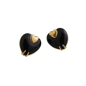 Boucles d'oreilles clous double cœur élégantes avec pierre noire et monture dorée.