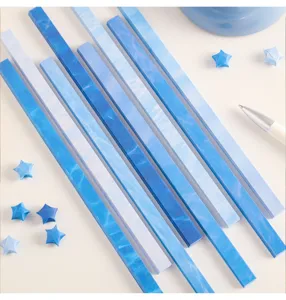 Close-up detail of blue gradient origami paper strips for lucky stars, neat flat lay view.