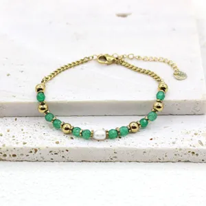 Macro view of freshwater pearl and green natural stone beads on a gold titanium steel bracelet.