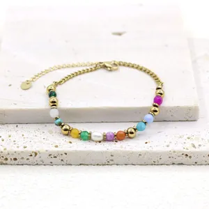 Close-up detail of a colorful natural stone and freshwater pearl gold chain bracelet.