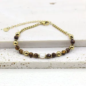 Detailed close-up showing the texture of tiger eye beads and a pearl on a golden dainty bracelet