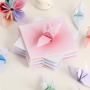 Nahaufnahme von bunten quadratischen Origami-Papierstapeln mit handgemachten Papierkranichen.