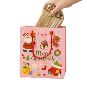 Pink Christmas paper gift bag with cute cartoon Santa and reindeer designs for holiday presents.