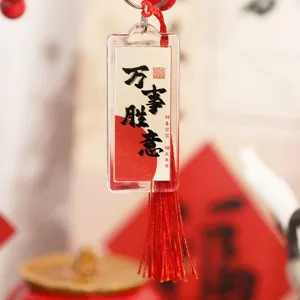 Nahaufnahme des chinesischen Acryl-Schlüsselanhängers mit Kalligraphie und roter Quaste.