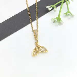 Dettaglio della collana con ciondolo a coda di pesce dorata con zirconi scintillanti e catena.