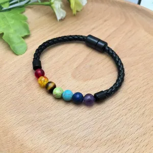 Primo piano perle chakra multicolore e chiusura magnetica sul braccialetto in pelle intrecciata nera.
