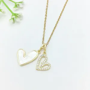 Primo piano di collana con ciondolo a doppio cuore, inserto bianco e zirconi lucidi.